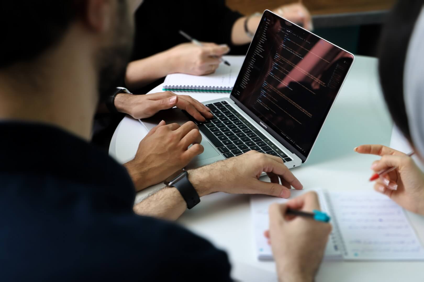 a group of people sitting around a laptop computer